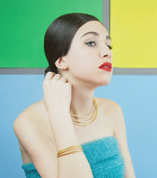 Vídeo: modelo con la pulsera y la gargantilla Sumatra triple doradas mate, fondo verde, amarillo y azul